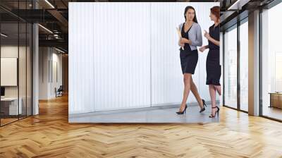 Meeting time. Two colleagues walking together in the office while have a conversation. Wall mural