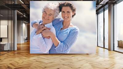 Woman, senior mother and portrait by sky with hug, happiness, love or smile for mothers day on vacation. Elderly lady, daughter or happy with care, bond or outdoor by clouds for holiday in retirement Wall mural