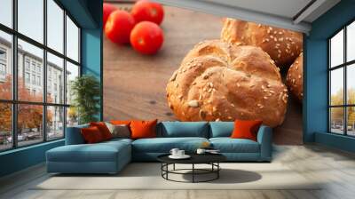 Delicious buns with sesame and cherry tomatoes on a cutting board. Wall mural