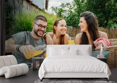 Group of three friends or family having picnic in backyard or garden Wall mural