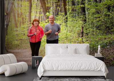 Husbanf and wife wearing sportswear and running in forest Wall mural