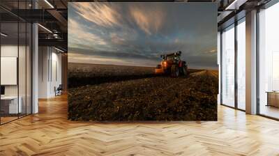 Tractor plowing fields in sunset Wall mural