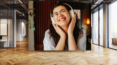 One young girl or woman is listening to music on her wireless headphones in the morning before going to work	 Wall mural