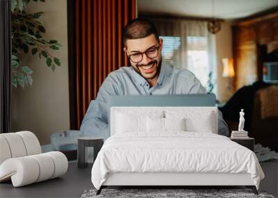 Young caucasian businessman working from home on laptop Wall mural