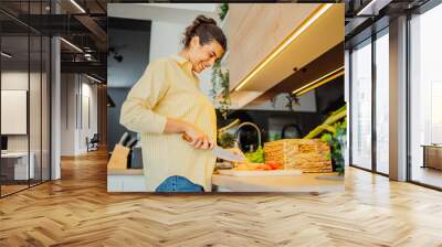 Young caucasian woman cutting vegetables in the kitchen Wall mural