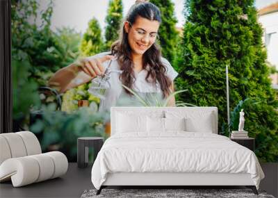 Young woman taking care of plants with water can and mister Wall mural