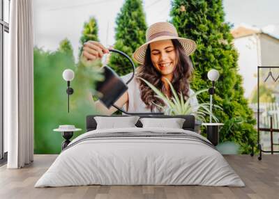 Young woman taking care of plants with water can and mister Wall mural