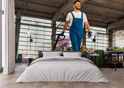 Caucasian professional male mechanic pulls, trolley with repair parts. Service, maintenance, people concept. Side view. Selective focus. Web Banner Wall mural