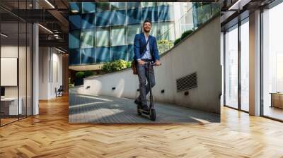 Young business man in a suit riding an electric scooter on a business meeting. Ecological transportation concept Wall mural