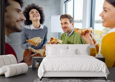 A cheerful group of colleagues laughing on a lunch break at the office. Wall mural