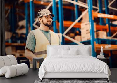 A delivery service worker with voice picking headset driving a forklift at storage. Wall mural