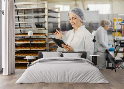 A food factory supervisor is doing quality control of cookies in facility. Wall mural