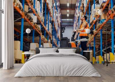 A forklift driver is collecting and organizing boxes with goods in storage. Wall mural