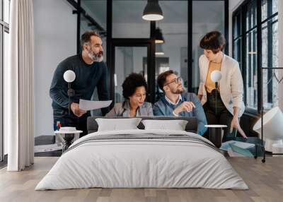 A group of businesspeople is standing and sitting at the office and working on project on a laptop. Wall mural