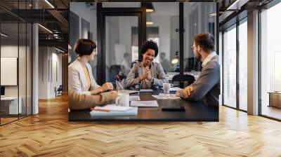 A happy interracial team is sitting at boardroom with manager and working on a project. Wall mural