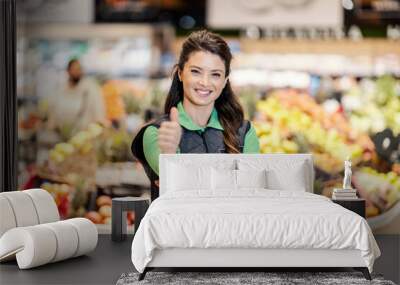 A happy manager at supermarket giving thumbs up and smiling at the camera. Wall mural