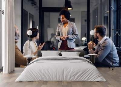 A multiracial female team leader is having business meeting with employees in the office. Wall mural