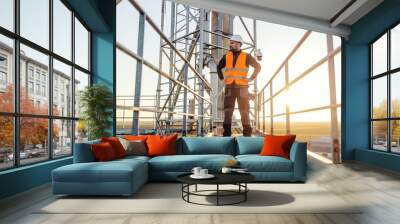 A proud height works worker is standing on top of the metal construction an looking at horizon. Wall mural