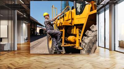 A senior heavy industry worker is climbing the bulldozer and getting ready to drive it. A driver climbing the bulldozer. Wall mural