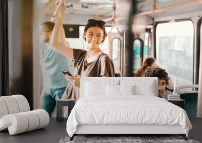 Caucasian girl driving in public bus and using smart phone for reading or writing message. Wall mural