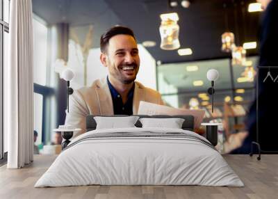 Cheerful young man looks happy after doing all paper work. Wall mural