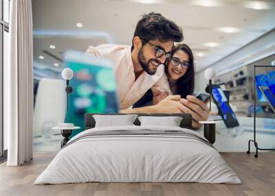 close up focus view of a cheerful charming happy young student love couple choosing a new mobile in  Wall mural