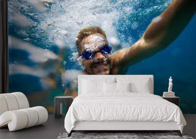 Energy man with smile taking a selfie photo underwater during summer. Wall mural