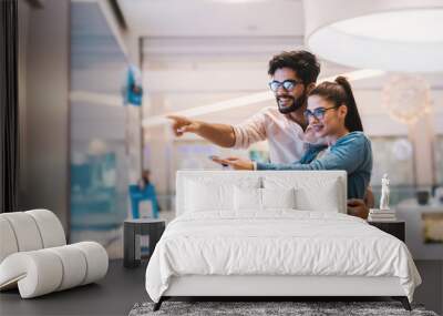 Excited young couple looking at big TV screen for their new home.at tech store Wall mural