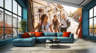 four attractive students enjoying a sunny day of a vacation in another city. Wall mural