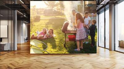 Grandfather teaching his grandchildren how to grill meal. Family gathering in backyard concept. Wall mural