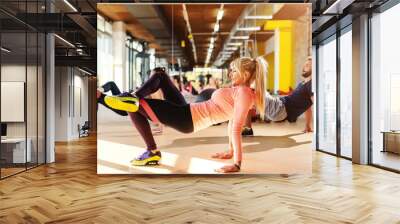 Group of sporty people with healthy habits doing strength exercises on the gym floor. In background mirror. Wall mural