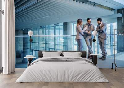 Group of successful real estate agents standing in building in construction process and looking at tablet. Man in the middle showing to his colleagues price on the market for that building. Wall mural