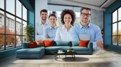 Multicultural group of business people standing with arms crossed in a row. Selective focus on man in foreground who is holding table tin hands. Wall mural