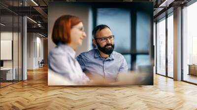 Portrait of an employee collaborating with colleague at office. Wall mural