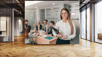 portrait of gorgeous businesswoman in formal wear, with long brown hair and eyeglasses holding clipb Wall mural