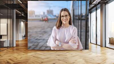 Portrait of gorgeous smiling Caucasian brunette dressed elegant standing with crossed arms on rooftop. Wall mural