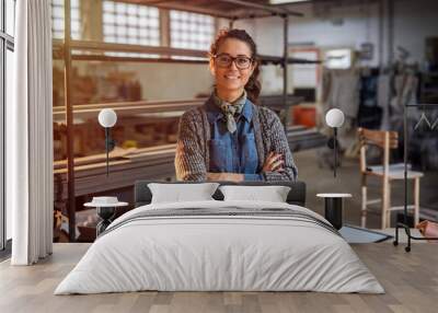 Strong confident middle aged woman engineer standing and looking at the camera at her workshop. Wall mural