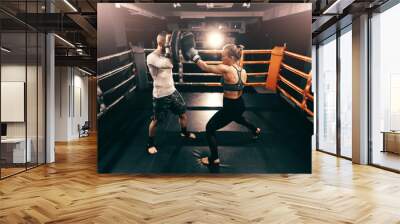 Strong muscular boxer Caucasian woman kicking and having training in ring. Wall mural