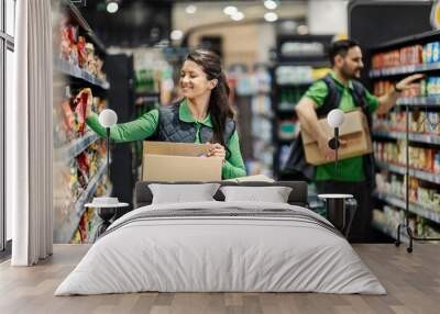 The employees arranging groceries on shelves in supermarket. Wall mural