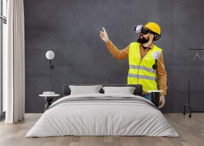 Young bearded constructor in working wear having virtual reality experience and showing up with his finger. Wall mural