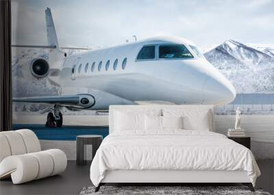 White luxury business jet on airport apron in winter on the background of high scenic snow capped mountains Wall mural