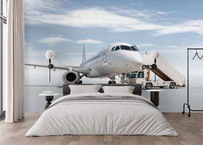 White passenger airplane with a boarding steps isolated on bright background with sky Wall mural