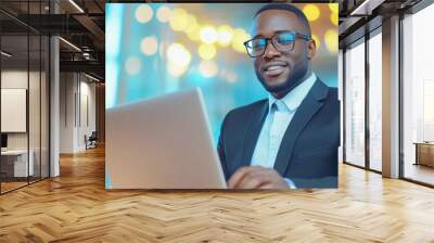 Professional young man working on laptop, smiling confidently in modern office setting.. Wall mural