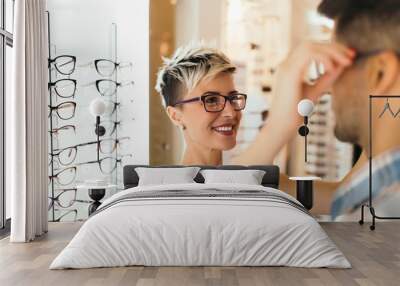 Attractive young couple in optical store buying glasses and smiling Wall mural