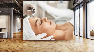 Beautiful brunette getting oxygen face therapy in a beauty salon. Professional skin care treatment. Wall mural