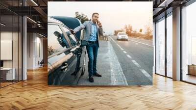 Elegant middle age business man calling towing service for help on the road. Roadside assistance concept. Wall mural