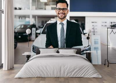 Good looking, cheerful and friendly salesman poses in a car salon or showroom. Wall mural