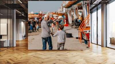 Grandfather and grandson having fun and spending good quality time together in amusement park. Wall mural