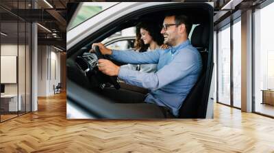 Happy middle age couple enjoying while choosing and buying new car at showroom. Wall mural