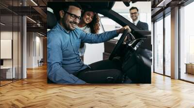 Middle age couple choosing and buying car at car showroom. Car salesman helps them to make right decision. Wall mural